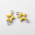 Macro view of two yellow enamel star charms with silver double loops for DIY jewelry - Yellow