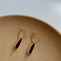 Boucles d'oreilles créoles dorées avec pendentifs trapèzes marron rouge sur un plateau - Bordeaux