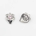 Detail eines Erdbeer-Anhängers mit rosa Herz-Edelstein und silberner Metallstruktur - Rosa