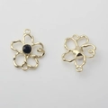 Makroaufnahme goldener hohler Blumenanhänger mit schwarzem Edelstein und Doppelringen - Schwarz mit Goldrand