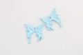 Detailed macro view of sky blue enamel butterfly charms with alloy metal texture - Blue Gold