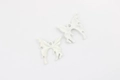 Detailed macro view of white butterfly alloy charms showing front and back texture - White