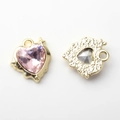 Macro-detail van hartvormige hanger met roze edelsteen en gouden metalen achterkant - Goud / Roze