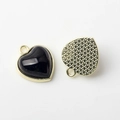 Detail of heart-shaped gold pendants with black inlay and textured metal backing - Black Gold