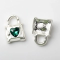 Detailed macro view of silver handbag charm with green heart crystal and hollow honeycomb back - Green Zircon