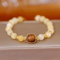 Bracelet ethnique avec perles jaune clair et élément central en bois sur socle doré - Style Bois d'Agar