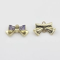 Detailansicht goldener Schleifenanhänger mit lila Kristallen und doppelten Hängeschlaufen - Lila-Gold