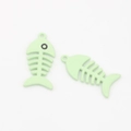 Macro detail of two light mint green fish bone pendants with a matte finish for DIY jewelry - Green