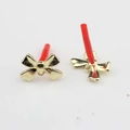 Detail of golden metal bow earring studs with protective red caps and hanging loops - Gold
