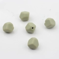 Dettaglio di cinque perle sfaccettate in silicone verde salvia per creazioni gioielli DIY - verde oliva