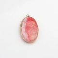 Macro shot of oval pink agate pendant with golden metal edges and natural textures - Pink
