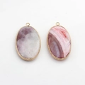 Macro shot of oval agate pendants with gold metal frames and detailed natural stone textures - Purple