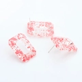 Detailed macro view of rectangular resin chain earrings with pink ink splash texture - Red