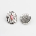 Macro detail of vintage silver oval button with pink stone and sunburst pattern - Pink