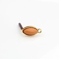 Macro detail of vintage gold horse-eye resin earring connector with amber stone inlay - Orange