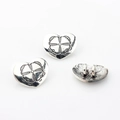 Macro shot of vintage heart-shaped alloy pendant charms with intricate floral engraving - Antique Silver