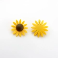 Détail macro de boucles d'oreilles tournesol jaunes montrant la texture mate et l'attache - Jaune