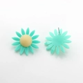Vue macro de boucles d'oreilles marguerites avec pétales en résine bleue et coeur jaune - Vert clair
