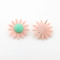 Gros plan de boucles d'oreilles marguerites en résine rose avec cœur vert et tige en métal - Rose