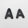 Macro shot of black acrylic letter A stud earrings with metal pins on a grey background - Letter Stud Earrings / Black