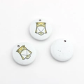 Macro view of three round wooden owl charms with geometric painting and pre-drilled holes - Owl