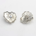 Macro shot of vintage silver heart-shaped button with lace texture and central bead detail - Marble White