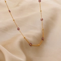 Gold chain necklace featuring purple beaded flower charms on a beige silk background - 18K Gold with Purple Zirconia