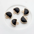 Detailed macro view of five black faceted stone pendants with gold metal edge on white plate - Black