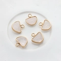 Macro view of five pink semi-circle gemstone pendants with gold-plated metal borders - Opal