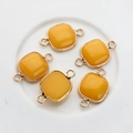 Macro detail of square yellow gemstone connectors with gold-plated metal frame for DIY jewelry - Yellow