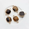 Macro shot of tiger eye stone pendants with gold plated square frames and double loops - Brown