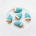 Detail van vijf blauwe turquoise hangers in tandvorm met goudkleurige metalen kapjes - Hemelsblauw