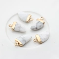 Detail van vijf witte wolfstand stenen hangers met gouden kappen op keramiek - Broken Wit