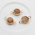 Close-up of three gold-rimmed picture stone connectors for DIY jewelry making - Brown