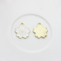 Macro detail of white enamel cherry blossom pendants with golden alloy floral backing - White