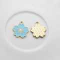 Macro detail of cherry blossom alloy charms with blue enamel and textured gold back - Blue