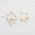 Macro detail of gold eye-shaped hollow charms with lashes and size dimensions - Gilded Small