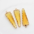Detalle macro de colgantes triangulares de cristal amarillo con bordes dorados - Amarillo