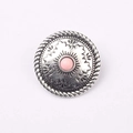 Dettaglio di un concho tondo in argento antico con resina rosa e rilievo floreale - Rosa