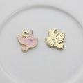 Detail of pigeon shaped metal charms with pink enamel and textured golden backside - Pink
