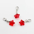 Close-up of three red crystal star pendants with silver lobster clasps on white background - Red