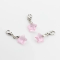 Macro shot of three pink crystal star charms with silver lobster clasps on white background - Pink