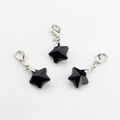 Close-up of three black faceted crystal star charms with silver lobster clasps for jewelry - Black