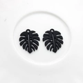 Close-up of matte black hollow monstera leaf pendants for DIY earring jewelry making - Black