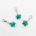 Close-up of three green crystal star pendants with silver lobster clasps on white background - Peacock Green