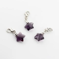Close-up of three purple crystal star pendants with silver lobster clasps on white background - Violet