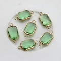 Macro shot of rectangular green faceted crystal connector with gold-plated copper edges - Fruit Green
