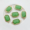 Macro shot of rectangular emerald faceted crystal charms with gold edges and dual rings - Green Jade