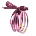 Detalle macro de cinco brazaletes de silicona con purpurina rosa y lazo de satén morado - Rojo Púrpura