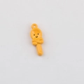 Close-up of yellow lollipop pendant with smiley face and bow for DIY jewelry making - Orange